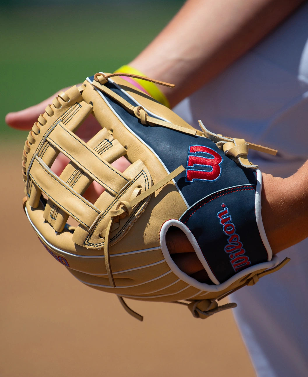 A tan and navy full grain leather Wilson A900 12″ Baseball Glove: WBG04101RT12 worn on a player’s hand, designed with a Pedroia Fit.