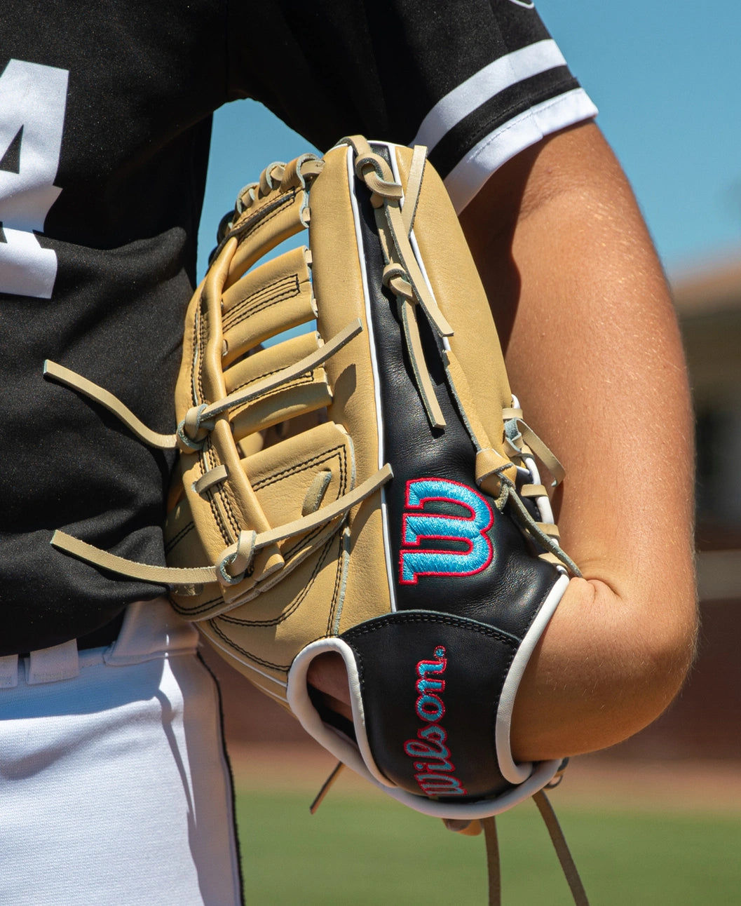 A baseball player wearing a tan and black Wilson A700 12.5″ Baseball Glove: WBG04601RT125 on their left hand.