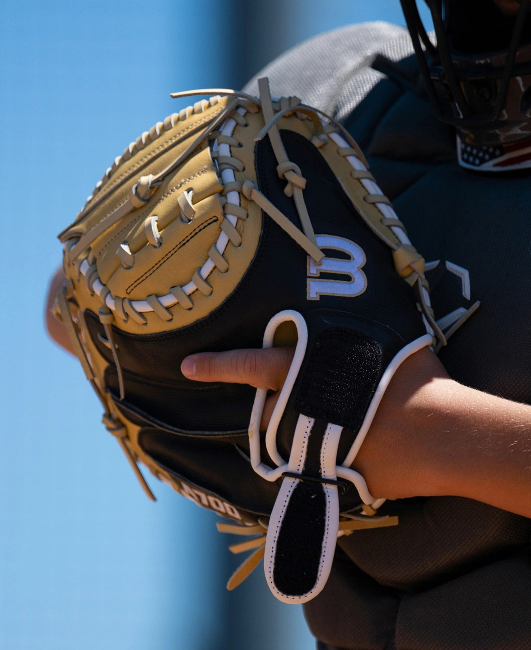 A close-up of a tan and black Wilson A700 32.5″ Baseball Catcher’s Mitt: WBG04701RT325 being worn on a hand.