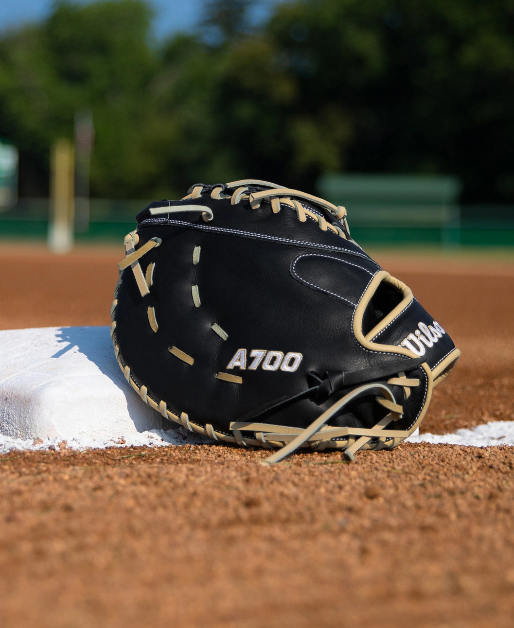 Black full grain leather Wilson A700 12″ Baseball First Base Mitt: WBG04801RT1620 with tan lacing resting on a white baseball base.