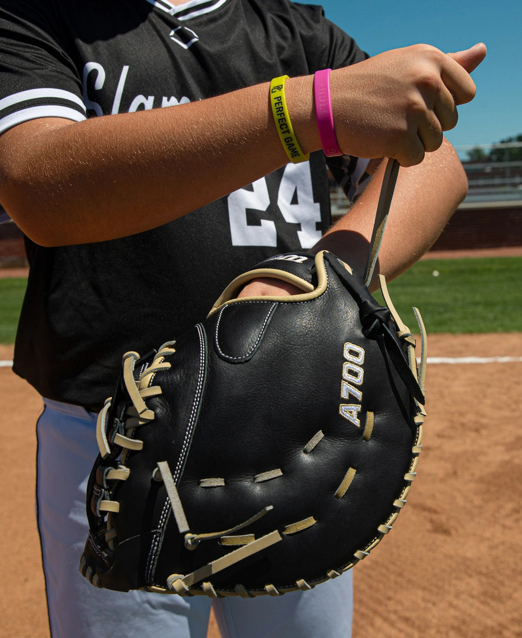 A baseball player holding a black Wilson A700 12″ Baseball First Base Mitt: WBG04801RT1620 with tan laces.