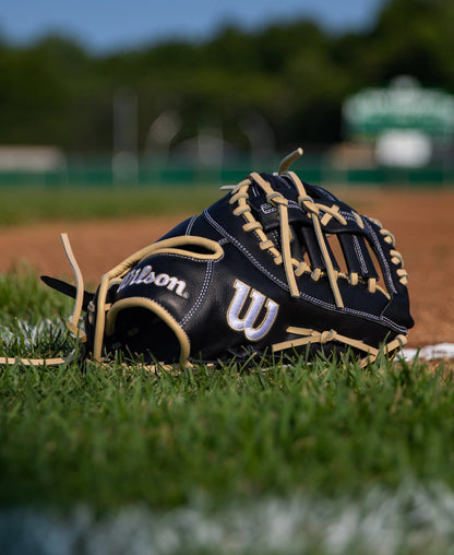 A black and tan Wilson A700 12″ Baseball First Base Mitt: WBG04801RT1620 resting on a grassy field.