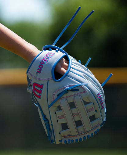 A light blue Wilson A700 12″ Fastpitch Glove: WBG04901RT12 with pink stitching and blue lacing worn on a hand.