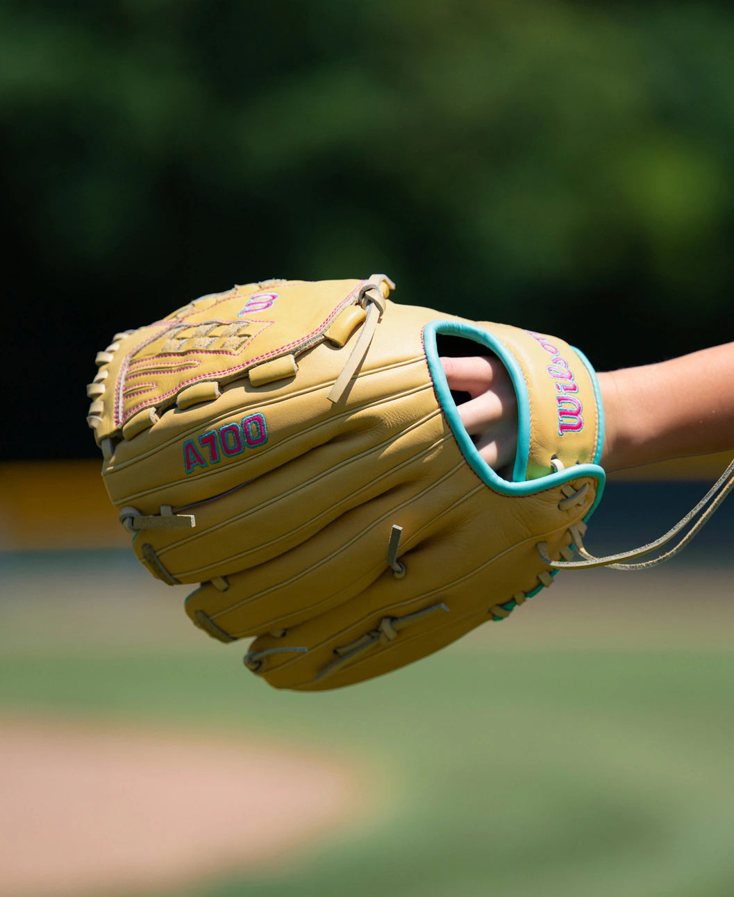 A tan and teal Wilson A700 12.5″ Fastpitch Glove: WBG05001RT125 crafted from full grain leather worn on a hand.