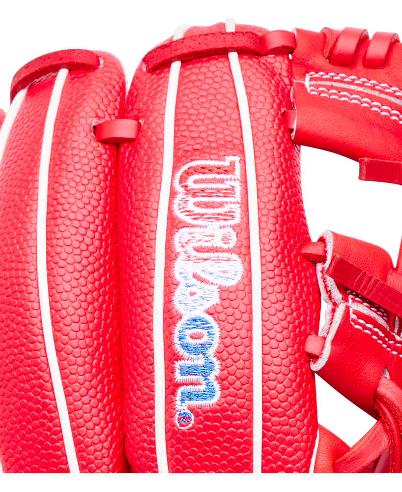 Close-up of a bright red Wilson A1000 PF11SS 11″ Baseball Glove with white piping and the manufacturer’s logo embroidered in blue and white on the wrist strap.