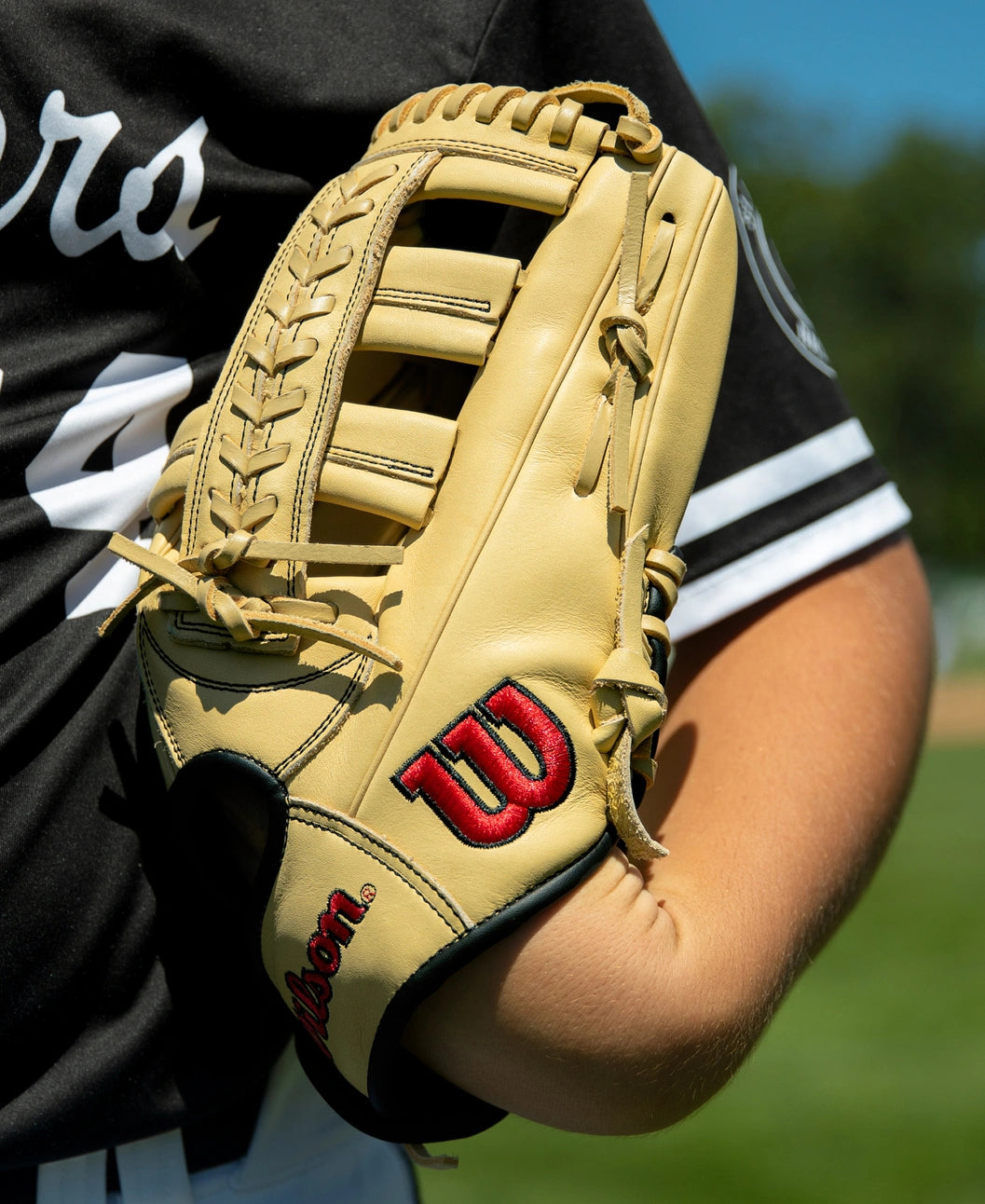 A tan Wilson A1000 1892 12.25″ Baseball Glove: WBG05301RT1225 worn on a player’s hand.