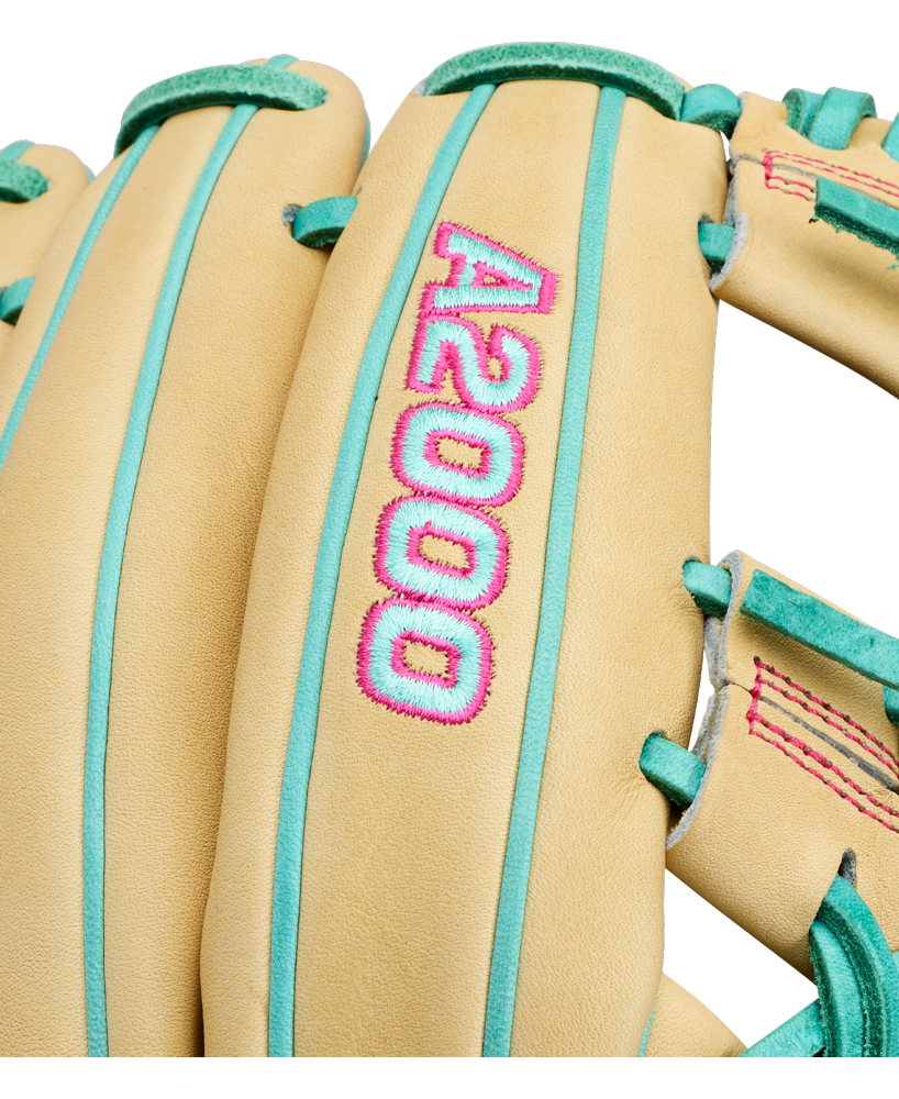 Close-up of a tan Wilson A2000 1975 11.75″ Baseball Glove (WBG05701RT1175) featuring teal laces, pink stitching, and an extra deep pocket. Bold pink and teal “A2000” embroidery adds a striking touch to this premium infield glove from Wilson.