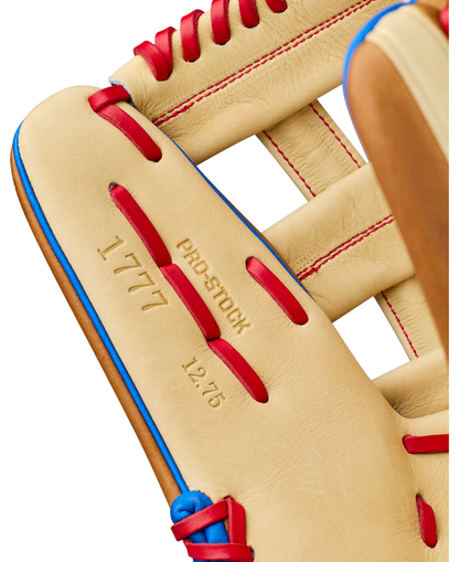 Close-up of a tan Wilson A2000 1777 12.75″ Baseball Glove (WBG06001RT1275) featuring Pro Stock leather with red and blue laces. The outfield glove is marked with PRO STOCK, 1777, and 12.75, highlighting its detailed stitching and textures.