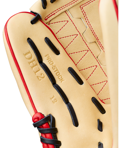 Close-up of a Wilson A2000 DH12 12″ baseball glove, crafted with Pro Stock leather and featuring red and black laces. The tan glove displays “DH12,” “PRO STOCK,” and “L2” stamped on the leather in gold lettering.