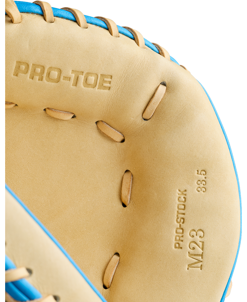 Here’s a revised version of the sentence using your product data: Close-up of the Wilson A2000 M23SS 33.5″ Baseball Catcher’s Mitt, featuring blue laces and tan leather embossed with PRO-TOE and PRO-STOCK M23 33.5—expertly crafted by Wilson for catcher’s mitt precision and outstanding pitch-framing skills.