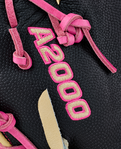Close-up of black textured leather on a Wilson A2000 1673SS 13″ Baseball First Base Mitt (WBG06301RT13) by Wilson, featuring pink A2000 embroidery and pink and beige suede laces threaded through it.