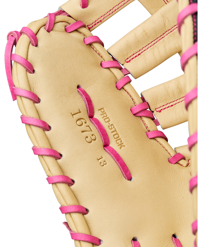 Close-up of a tan Wilson A2000 1673SS 13″ Baseball First Base Mitt (WBG06301RT13) with pink laces. The inside palm is stamped with PRO STOCK 1673 13” and features visible stitching detail, highlighting its design as a durable and dependable first base mitt from Wilson.