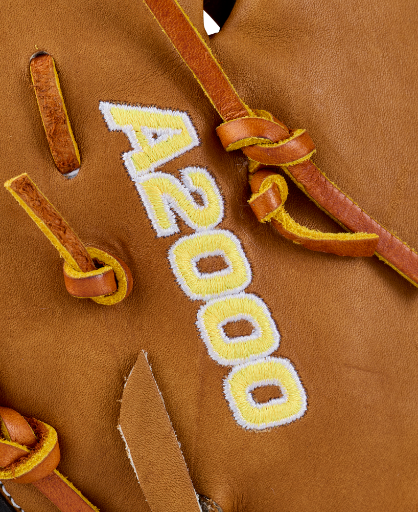 Close-up of a brown Wilson A2000 1677 12.5″ Baseball First Base Mitt (WBG06501RT125), featuring yellow and white embroidered “A2000” text and detailed lacing.