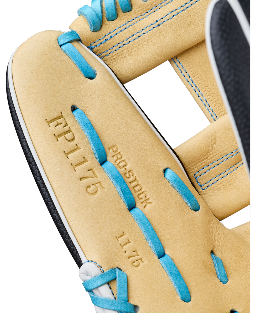 Close-up of a tan and black Wilson A2000 FP1175SS 11.75″ Fastpitch Glove (WBG06601RT1175) with blue laces. The glove features FP1175, PROSTOCK, and 11.75 stamped on the leather, with blue stitching visible along the seams.