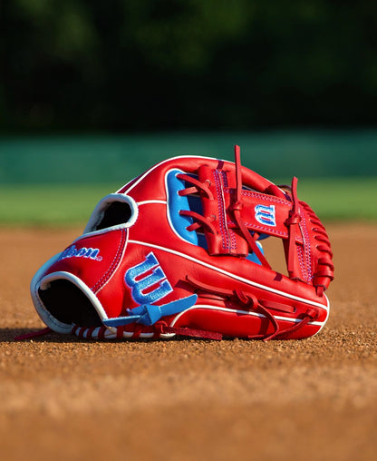 Red and blue Wilson A500 11″ Baseball Glove: WBG08501RT11 resting on a dirt field.