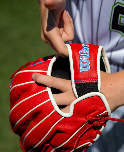 Wilson A500 11″ Baseball Glove: WBG08501RT11 youth infield glove in red with white piping and a blue-embroidered strap.