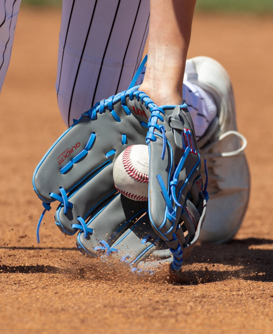 A baseball player slides into base while wearing a Wilson A500 12″ Baseball Glove: WBG08701RT12, which features full leather construction and bright blue lacing.