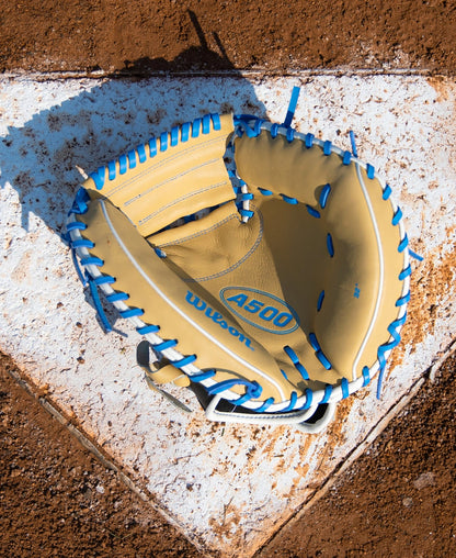 A tan Wilson A500 32″ Baseball Catcher’s Mitt: WBG08901RT32 with bright blue lacing, resting on a white home plate.