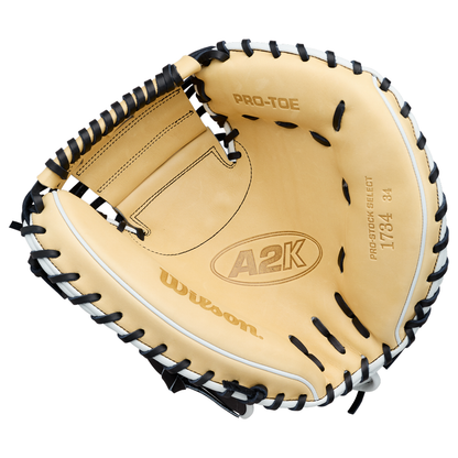 A tan and black Wilson A2K 1734 34″ Baseball Catcher’s Mitt (WBG10701RT34) is shown against a white background, featuring visible Pro-Stock Select and Pro-Toe text on the inside palm area and Double Palm Construction for added durability.