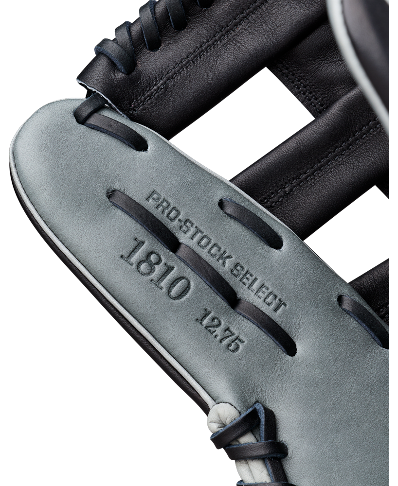 Close-up of a Wilson A2K 1810 12.75″ Baseball Glove (WBG10802RT1275) in gray and black, expertly crafted by Wilson from Pro Stock Select leather. The glove features embossed text—PRO-STOCK SELECT 1810 12.75—on the leather, with visible laces and detailed stitching, making it an ideal choice for outfielders seeking premium performance and durability.