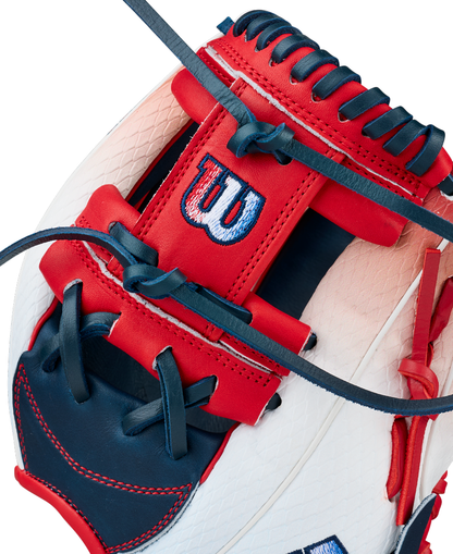 Close-up of the Wilson A1000 1787 FREEBIRD 2.0 11.75″ Baseball Glove (WBG26501RT1175) by Wilson, expertly crafted from red, white, and navy blue Full Grain leather with intricate stitching and a Wilson logo embroidered on the red strap. This premium infield glove delivers outstanding style and exceptional performance for dedicated players.