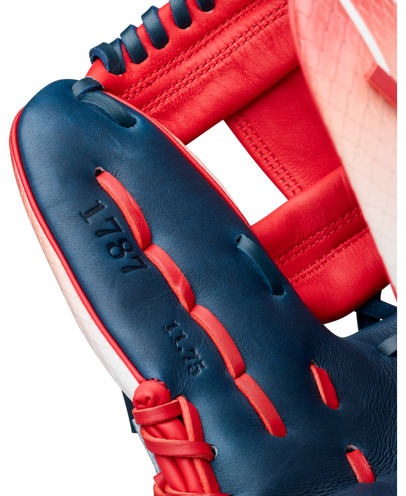 Close-up of the Wilson A1000 1787 FREEBIRD 2.0 11.75″ Baseball Glove (WBG26501RT1175) by Wilson, showcasing its red, white, and blue full grain leather design with “1787” and “11.75” engraved on the blue section, along with visible stitching and laces.