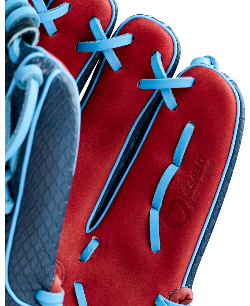 Close-up of a Wilson A1000 B23 GENO 12″ Baseball Glove (WBG26601RT12) in red, featuring blue laces, a textured dark blue interior, and an embossed “THE MOMENT” logo.