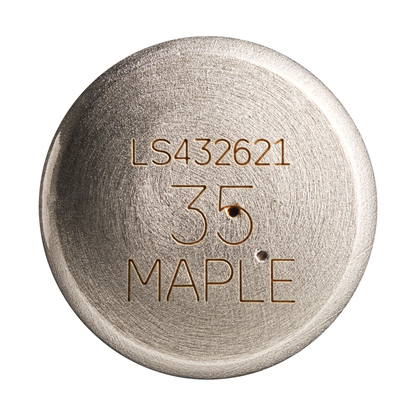 A round metallic object engraved with LS432621, 35, and MAPLE features a brushed texture and two small holes below the number, reminiscent of the classic craftsmanship of a Louisville Slugger Maple S345 Fungo 35″ Wood Training Bat.