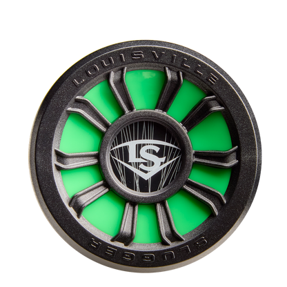 A close-up of the 2026 Louisville Slugger Dynasty (-3) BBCOR Baseball Bat shows a round, green and black design with spokes and the LS logo at the center. "Louisville" and "Slugger" appear on the rim, reflecting its quality brand.