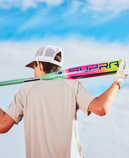 A person in a white cap and glove holds a colorful Louisville Slugger 2027 Supra (-8) USSSA Baseball Bat (WBL4252010) over their shoulders, facing away from the camera against a bright blue sky.