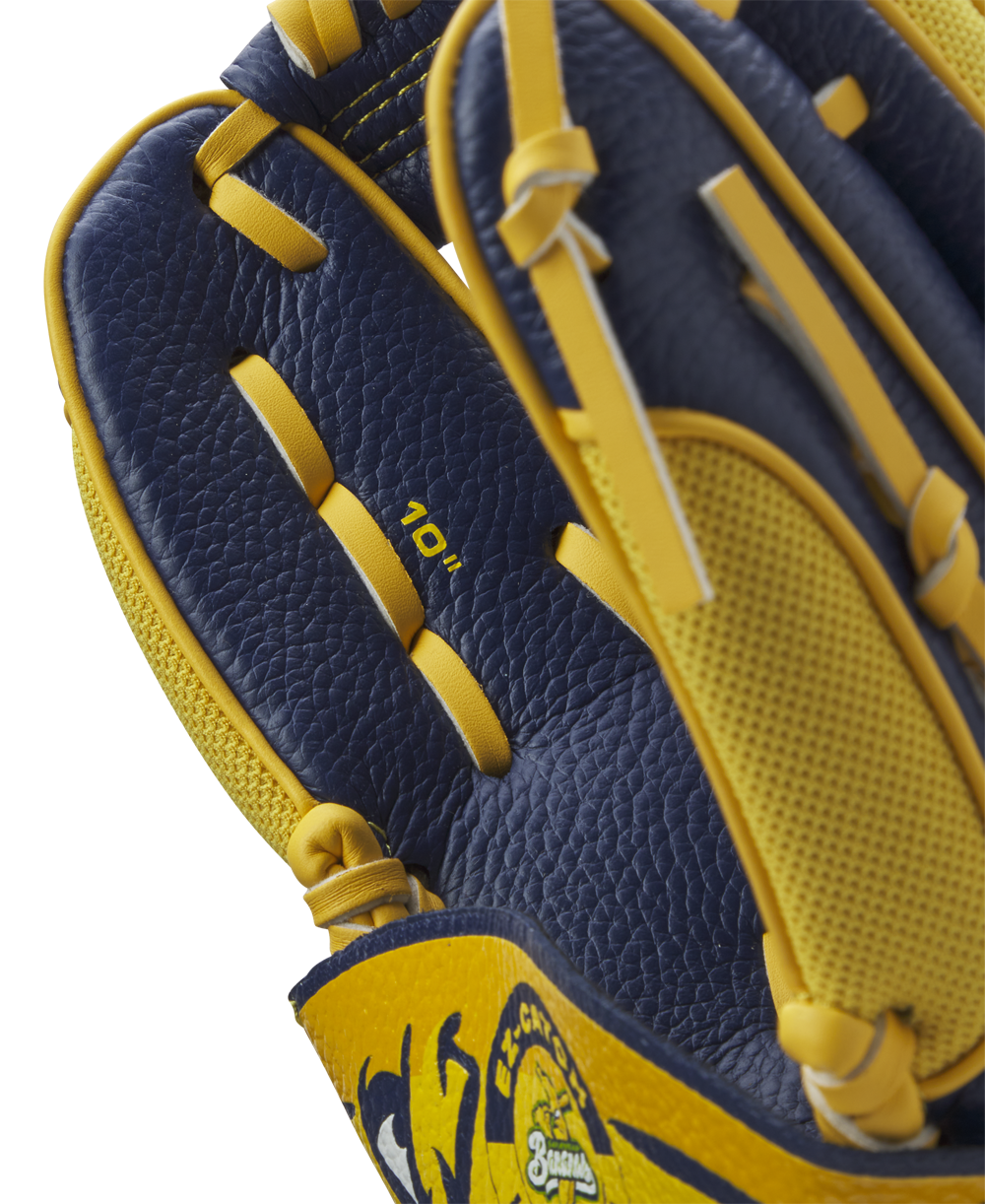 A close-up of the Wilson A200 EZ Catch Savannah Bananas 10" Youth Baseball Glove (WBW10135910) shows navy blue and yellow leather, detailed stitching, textured surface, an EZ Catch design, and "10”" printed inside.