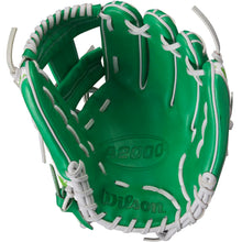 A Wilson A2000 1786 11.5" MDA Shamrocks baseball glove by Wilson is shown open, featuring green leather with white lacing and the brand name and model visible inside the palm.