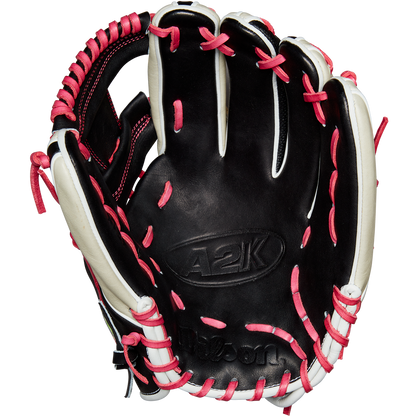 The Wilson A2K 1724 11.75" Baseball Glove (GOTM June 2024) by Wilson is shown open with black Pro Stock Select leather, white accents, and pink laces, displayed against a plain white background.