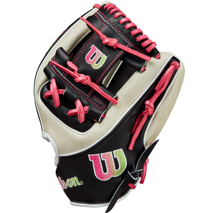 The Wilson A2K 1724 11.75" Baseball Glove GOTM June 2024 (WBW1022571175) features black, white, and pink Pro Stock Select leather, red laces, and green and pink “W” logos on the wrist and web; shown upright on a white background.