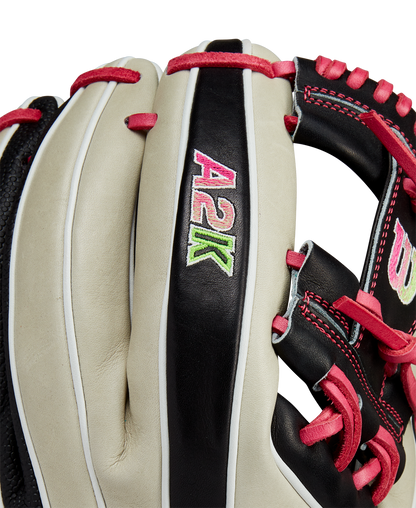 A close-up of the Wilson A2K 1724 11.75" Baseball Glove (GOTM June 2024, WBW1022571175) showcases Pro Stock Select leather in white and black, pink lacing, and "A2K" embroidered in pink, green, and white on a black strip.