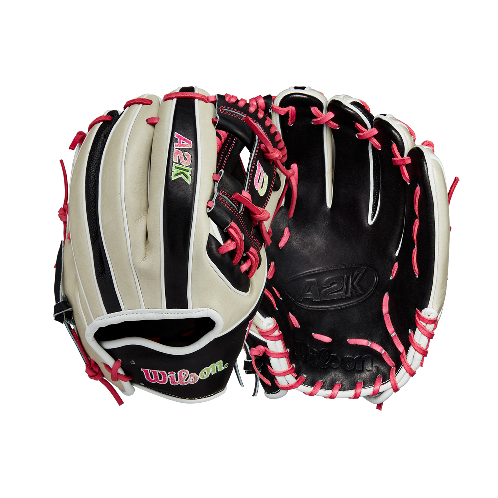 Two Wilson A2K 1724 11.75" GOTM June 2024 baseball gloves by Wilson, made with Pro Stock Select leather in black, beige, and pink, feature white/pink laces and green/pink embroidered logos. Front and back views shown.