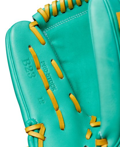 Close-up of a teal Wilson A2000 B23 12" Baseball Glove with yellow laces, featuring embossed B23 and prostock text on the palm. Crafted from Pro Stock leather with detailed stitching for FALL 2024 (WBW10227012).