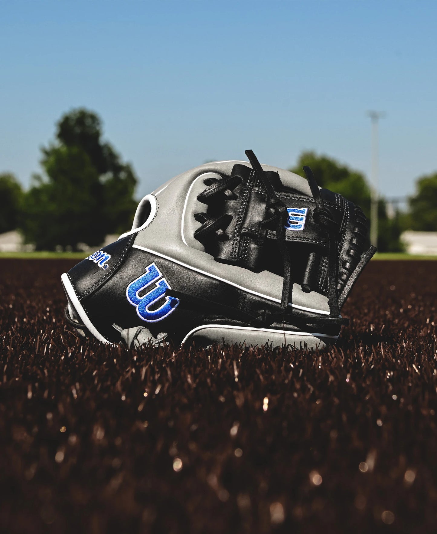 The Wilson A900 PF1125 11.25" Baseball Glove (WBW1025691125) by Wilson rests on the field, crafted for younger players seeking enhanced control and comfort.