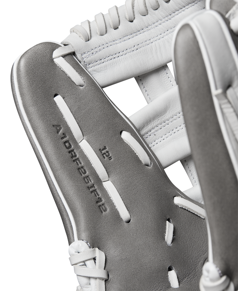 Close-up of a Wilson A1000 IF12 12" Fastpitch Glove by Wilson, featuring gray and white Full Grain leather, detailed stitching, laces, and embossed text WBW10259112 on the inside.