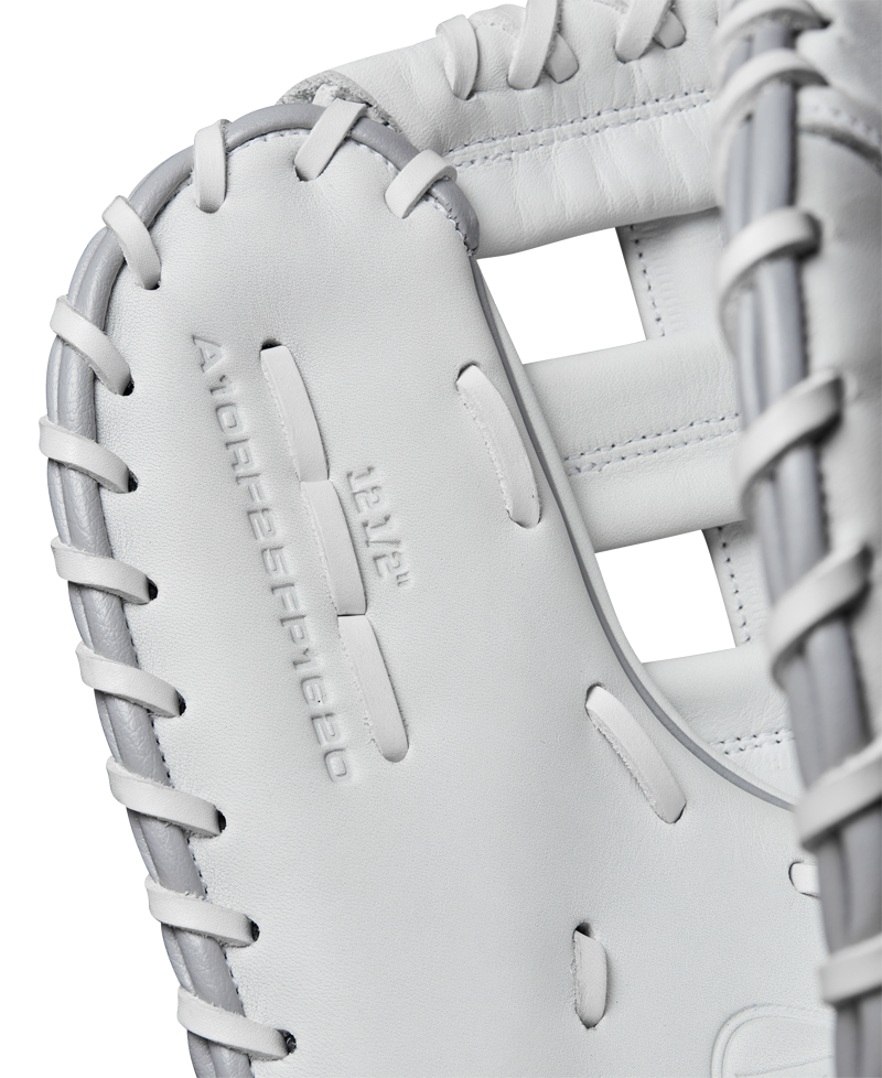 Close-up of a white Wilson A1000 1620 12.5" Fastpitch First Base Mitt (WBW102598125) in full grain leather with gray lacing, featuring embossed branding on the palm—ideal for fastpitch softball first basemen.