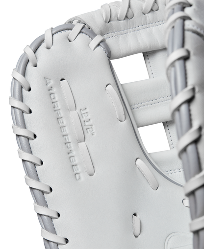 Close-up of a white Wilson A1000 1620 12.5" Fastpitch First Base Mitt (WBW102598125) in full grain leather with gray lacing, featuring embossed branding on the palm—ideal for fastpitch softball first basemen.