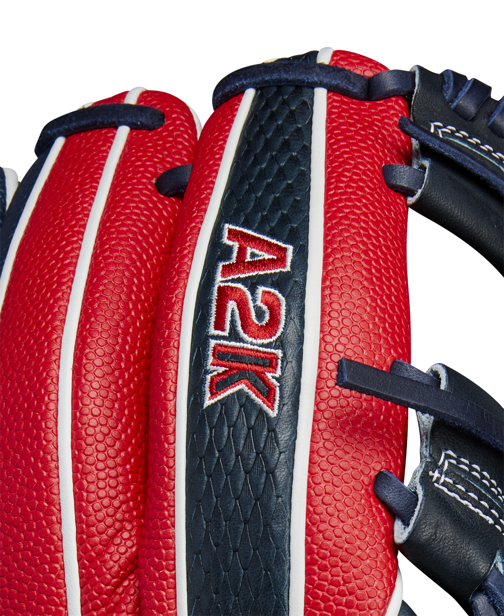 Close-up of the Wilson A2K 1724SS 11.75" Baseball Glove (FALL 2024) featuring red and navy blue Pro Stock Select leather, white stitching, black laces, textured surface, and "A2K" embroidered on the back.