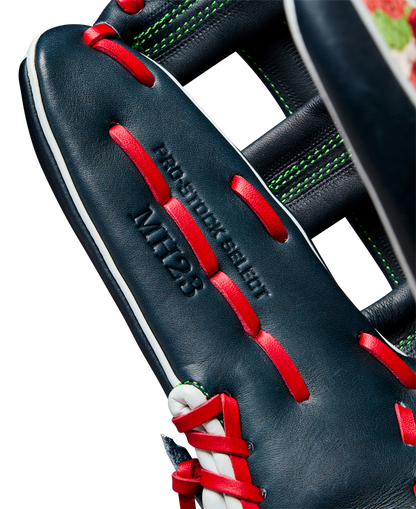 Close-up of a dark blue Wilson A2K MH23 12.75" Michael Harris GM baseball glove (WBW1026201275) with red laces, white stitching, and green accents. Made from Pro Stock Select leather and embossed with PRO STOCK SELECT and MTT23.