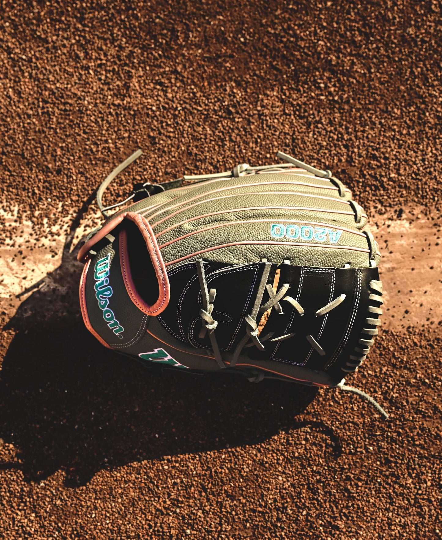 A Wilson A2000 MA14SS 12.25" Fastpitch Glove (WBW1027221225) by Wilson lies on the dirt infield next to a crisp white chalk baseline.