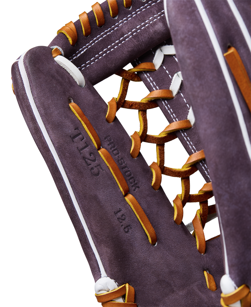 Close-up of a Wilson A2000 T125 12.5" Aliyah Andrews GM Fastpitch Glove (WBW102745125) in purple with orange laces and white stitching, featuring "11.25," "pro stock," and "12.6" stamped on the palm.