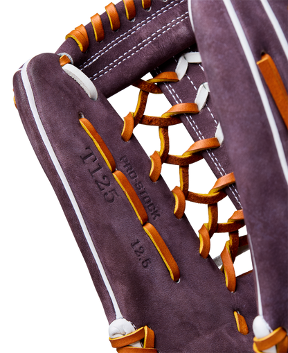 Close-up of a Wilson A2000 T125 12.5" Aliyah Andrews GM Fastpitch Glove (WBW102745125) in purple with orange laces and white stitching, featuring "11.25," "pro stock," and "12.6" stamped on the palm.