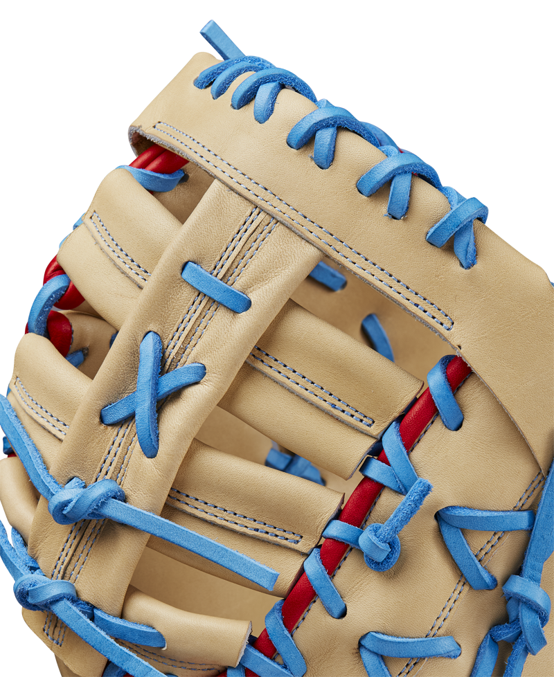 Close-up of the Wilson A2000 1677 12.5" First Base Mitt, featuring tan Pro Stock leather, bright blue laces, red accents, and detailed stitching with a woven web design. Model: WBW102753125, SPRING 2025.