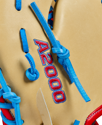 Close-up of a Wilson A2000 1677 12.5" first base mitt, crafted from Pro Stock leather, with tan color, blue laces, and red A2000 stitching. Model WBW102753125 from Wilson’s Spring 2025 lineup.