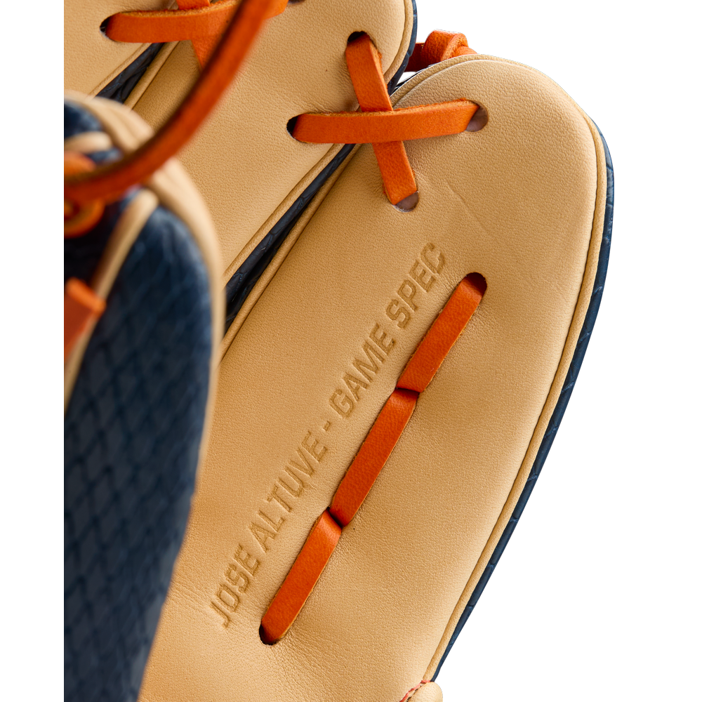Close-up of the Wilson A2000 JA27 11.5" Jose Altuve GM Baseball Glove featuring tan Pro Stock leather, orange laces, "JOSE ALTUVE - GAME SPEC" embossing, and navy textured trim. Model: WBW103295115, Summer 2025 release.