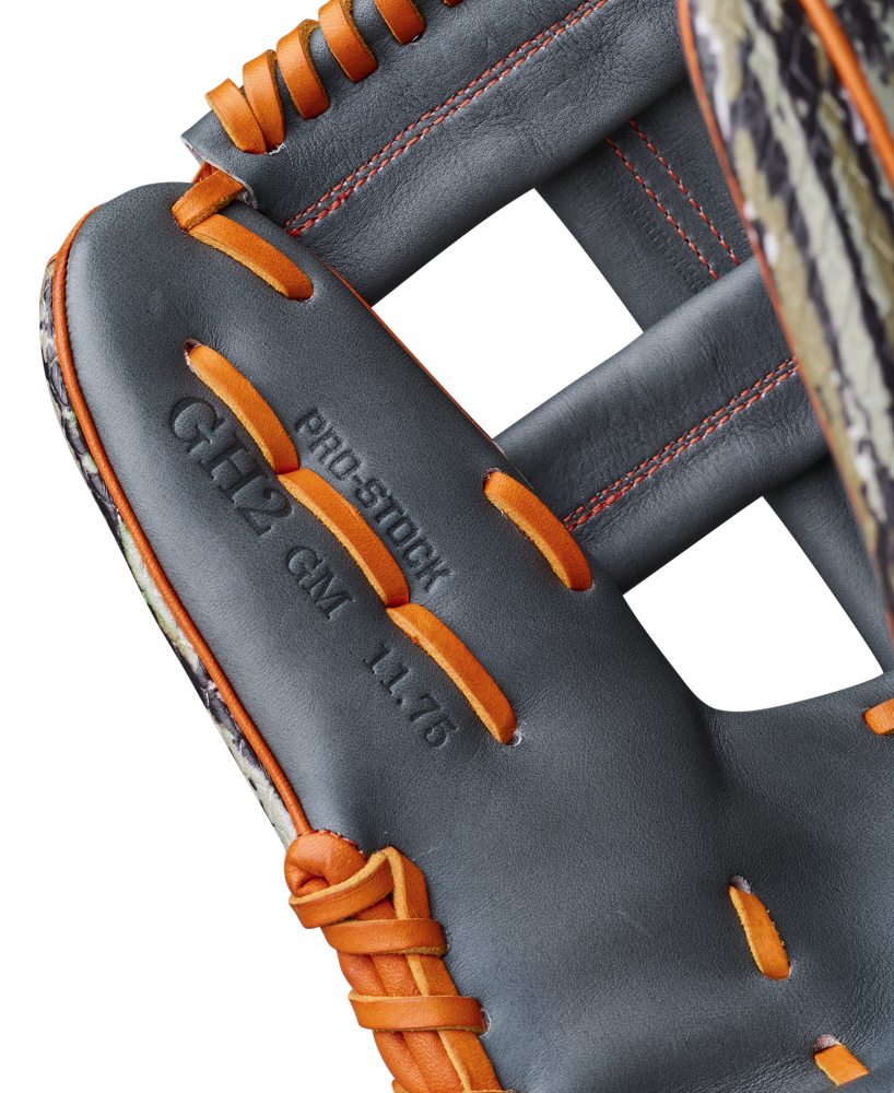Close-up of the Wilson A2000 GH2 11.75" Gunnar Henderson GM Baseball Glove (WBW1034511175), featuring black leather with orange laces and stitching, embossed "PRO STOCK GH12 GM 11.75" on the palm, and a patterned edge on the left side.